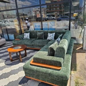 Green L-shape sectional corner sofa with tufted backrest and wooden trim displayed outdoors in Nairobi