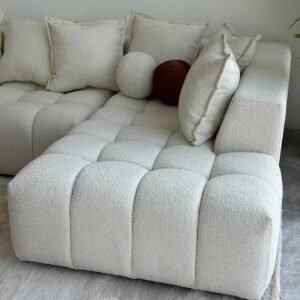 Ivory bouclé chaise sectional sofa with deep tufted seat and plush cushions in a modern living room.