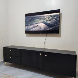 black modern TV cabinet with gold legs and storage drawers used as entertainment unit in a living room in Kenya