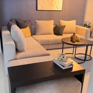 Beige L-shape sofa Kenya with cushioned seats, chaise section, loose pillows, and modern lounge styling