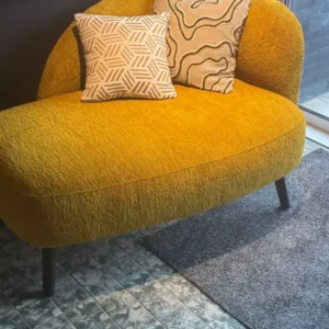 Mustard loveseat with rounded backrest, textured upholstery and black legs for Kenya interiors