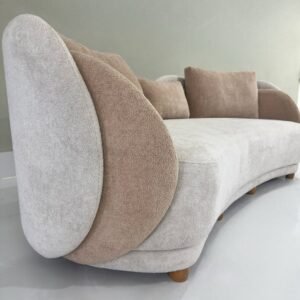 Cream curved chaise sofa with tan accents, loose cushions and wood-tone legs for Kenya lounges