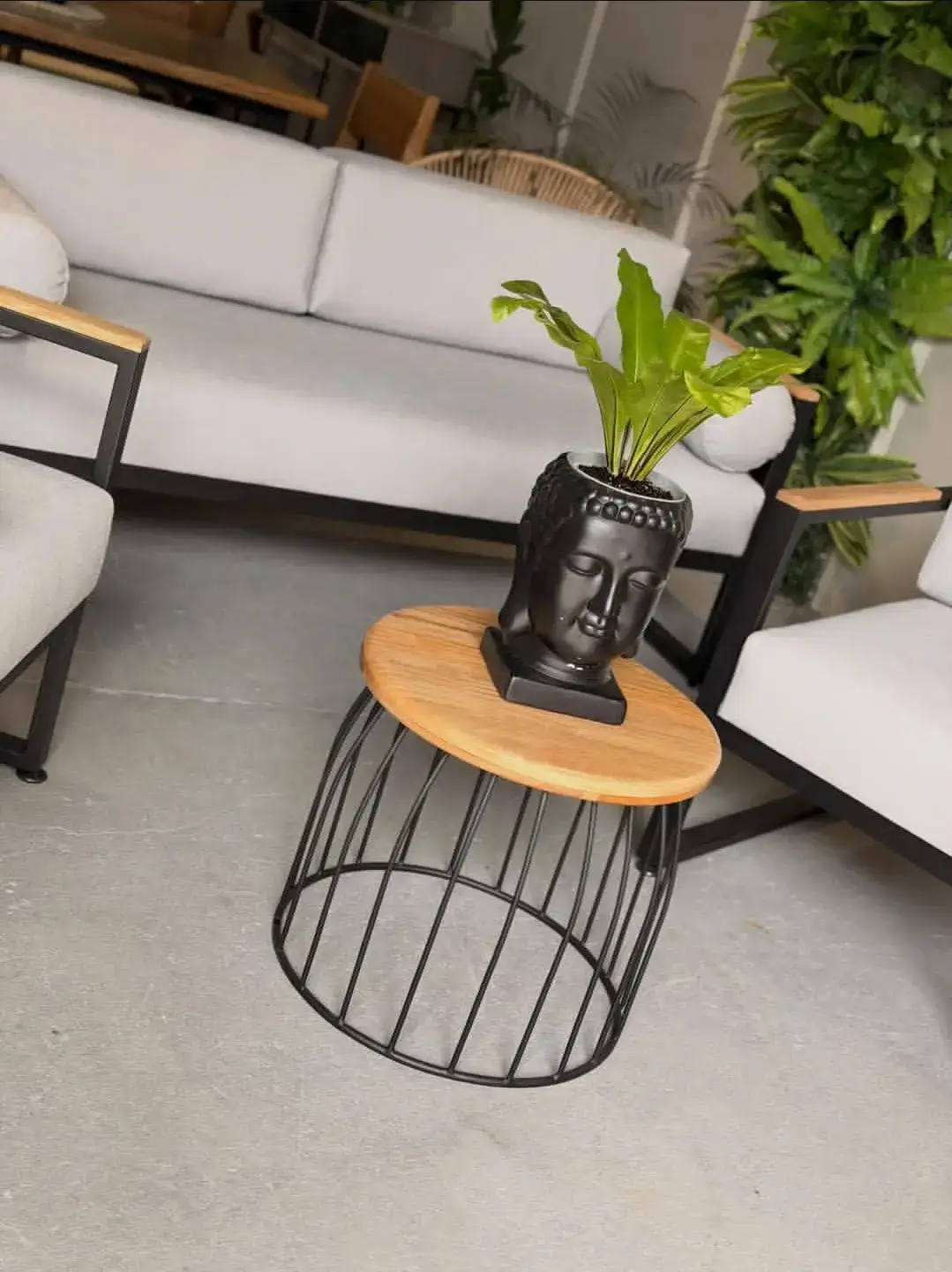 Round side table with wood-look top and black wire base for plant display in Kenya