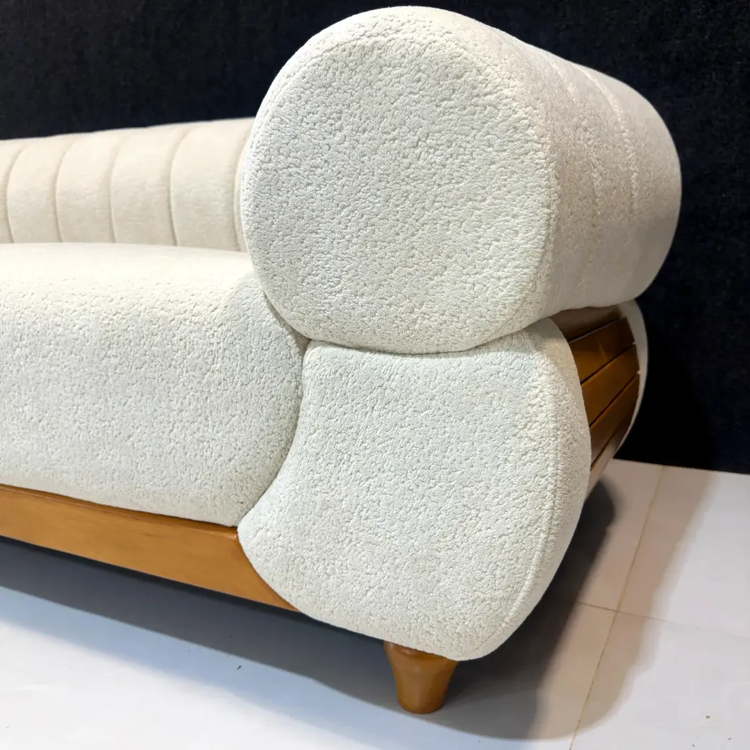Cream curved chaise sofa with tan accents, loose cushions and wood-tone legs for Kenya lounges