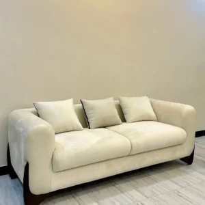Cream sofa set Kenya with rounded arms, throw pillows and dark curved base accents