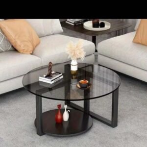 Round glass coffee table with black frame and lower shelf for Kenya living rooms