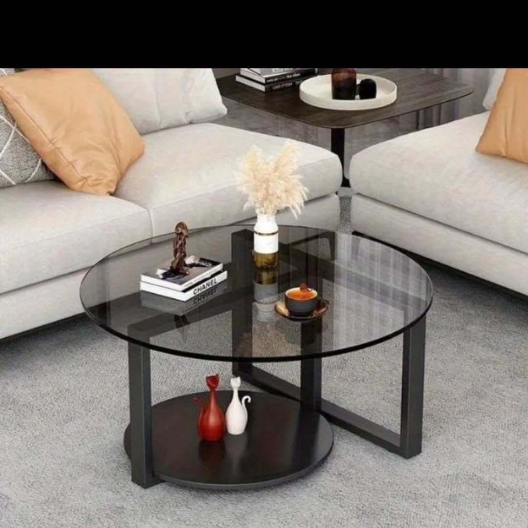 Round glass coffee table with black frame and lower shelf for Kenya living rooms