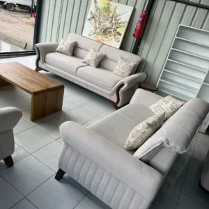 Light grey sofa set Kenya with rolled arms, wood-tone accents, ribbed detail, and patterned pillows