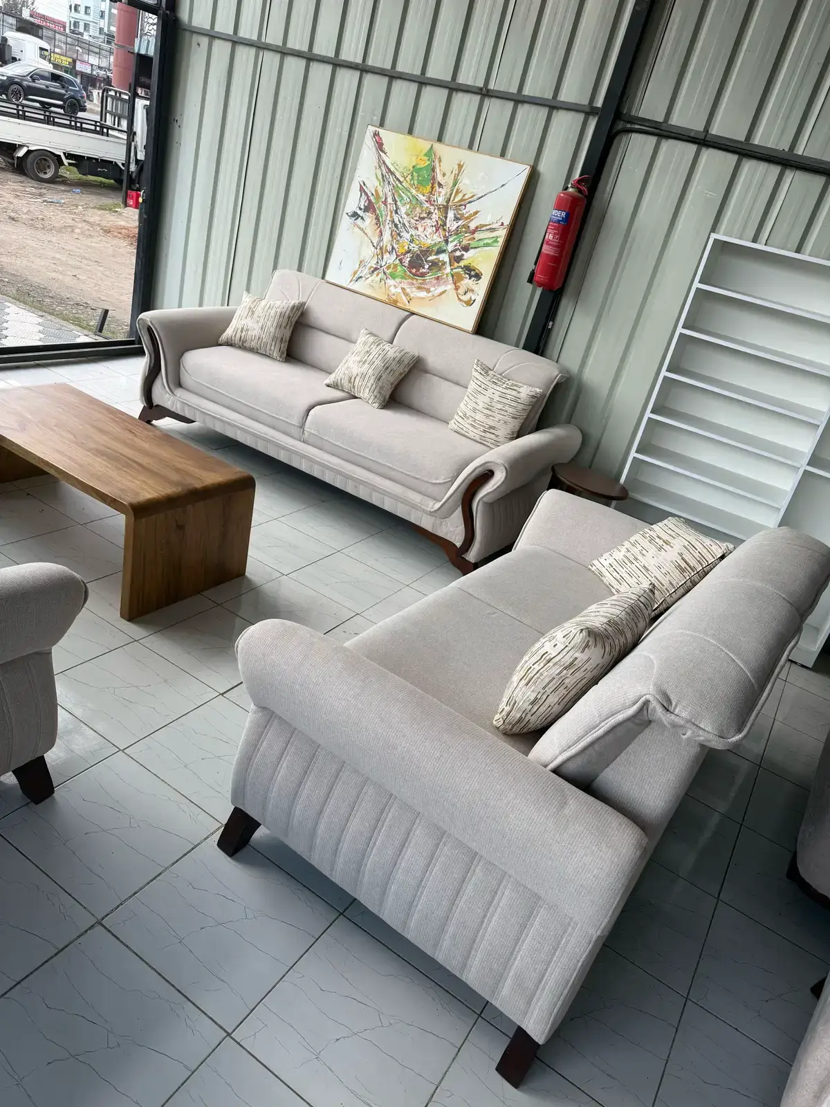 Light grey sofa set Kenya with rolled arms, wood-tone accents, ribbed detail, and patterned pillows