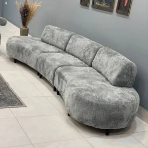 Curved grey sectional sofa with textured upholstery, rounded seating and black legs for Kenya living rooms