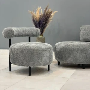 Grey accent chair with textured rounded seat, cylindrical backrest and black legs for Kenya interiors