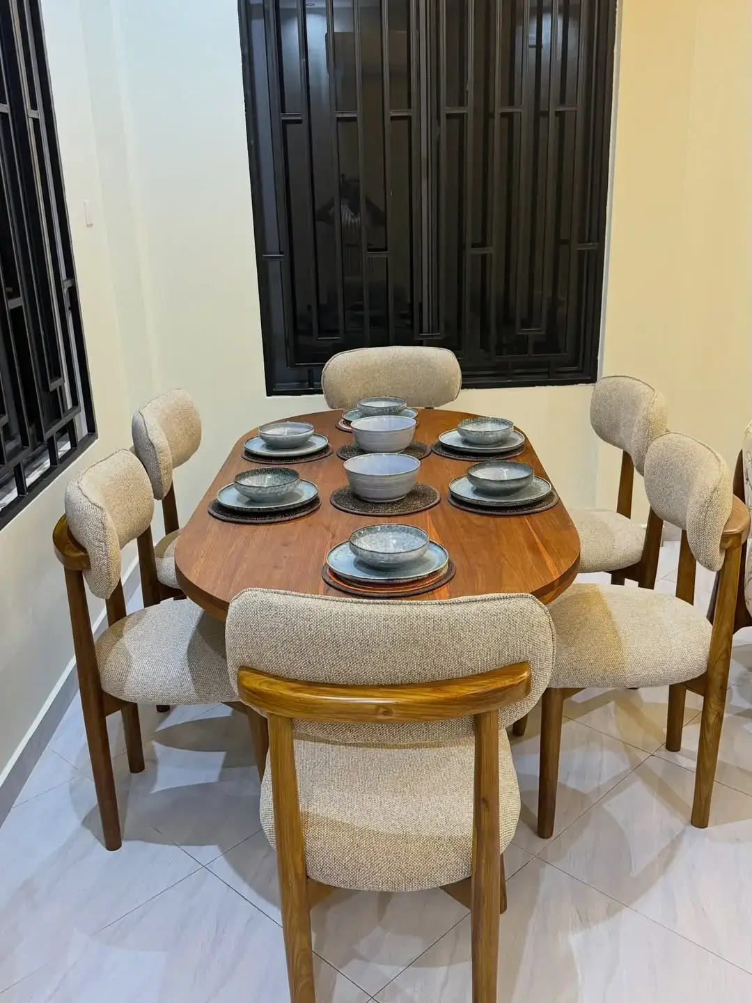 Wooden dining table set Kenya with rounded tabletop and upholstered curved chairs
