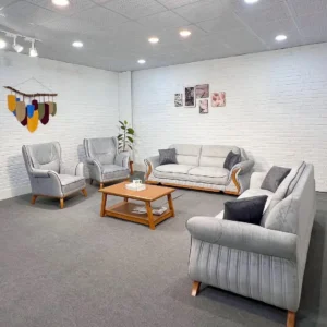 Light grey sofa set Kenya with curved arms, wood-tone accents, matching chairs, and cushioned seating