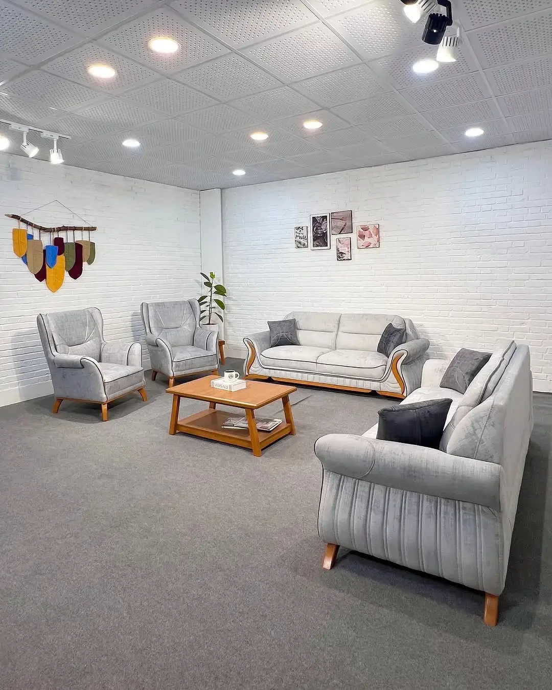Light grey sofa set Kenya with curved arms, wood-tone accents, matching chairs, and cushioned seating