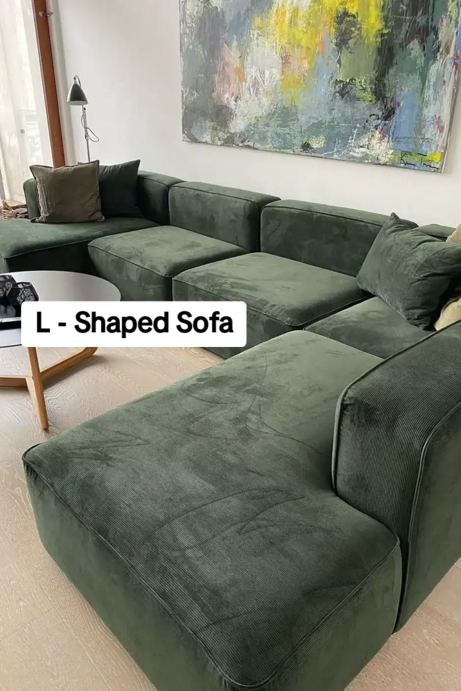 Deep forest green L-shaped sectional sofa with modular cushions in a modern living room