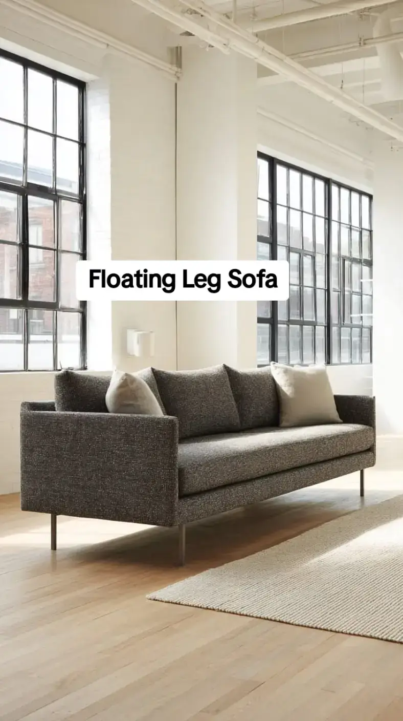 Charcoal boucle floating-leg sofa on slim metal pin legs in a bright industrial loft space