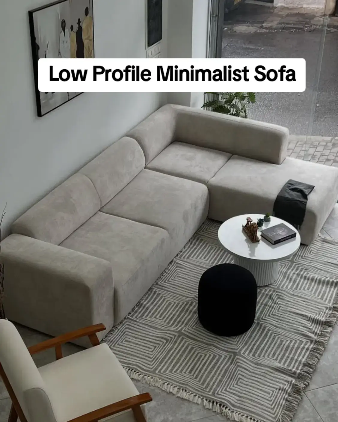 Sand low-profile L-shaped minimalist sofa with round coffee table and geometric rug — modern Nairobi room