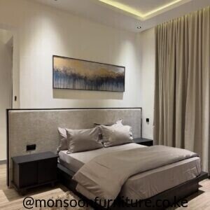 Beige wide-headboard bed Kenya with a low dark platform base, slim black trim and extended upholstered bedside backdrop