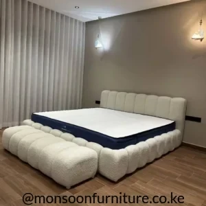 Cream bouclé bubble-panel 5×6 bed Kenya with rounded upholstered headboard, padded frame and matching ottoman