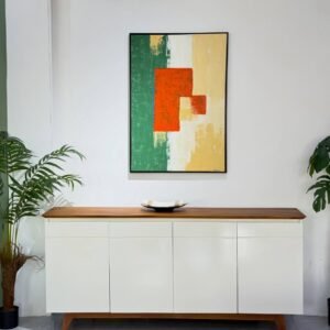 Framed abstract artwork in green, cream, orange and warm beige on a white interior wall.