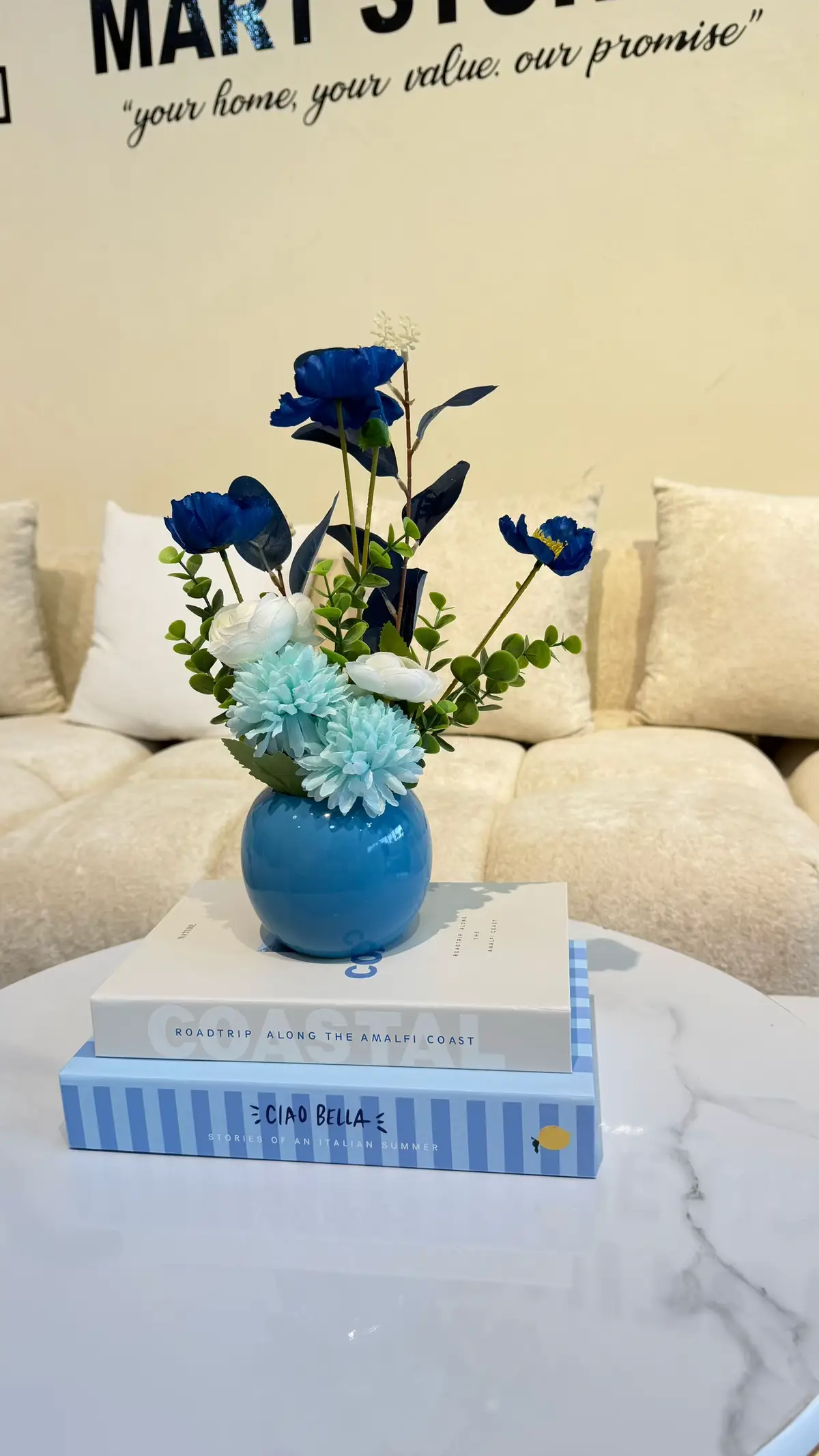 Wooden coffee table styled with a vase of greenery and stacked books in a bright living room