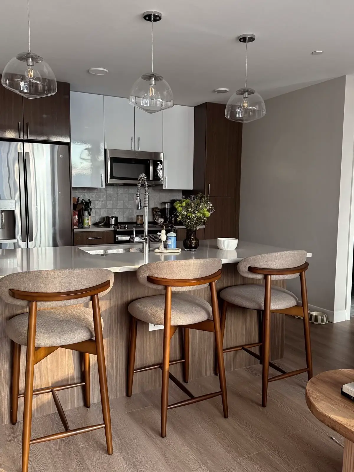 Styled kitchen counter with bar stools, pendant lights and a fruit bowl