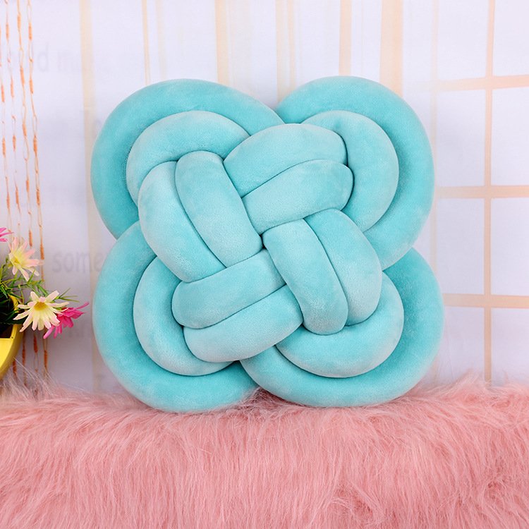 Six plush flower-knot cushions/throw pillows in charcoal, aqua, grey, white, blush and mint displayed on a pink seat in Nairobi