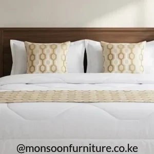 Beige geometric bed runner with two matching square decorative covers arranged on white bedding.