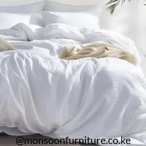 Plain white duvet with a relaxed draped finish arranged on a bed with white pillows.