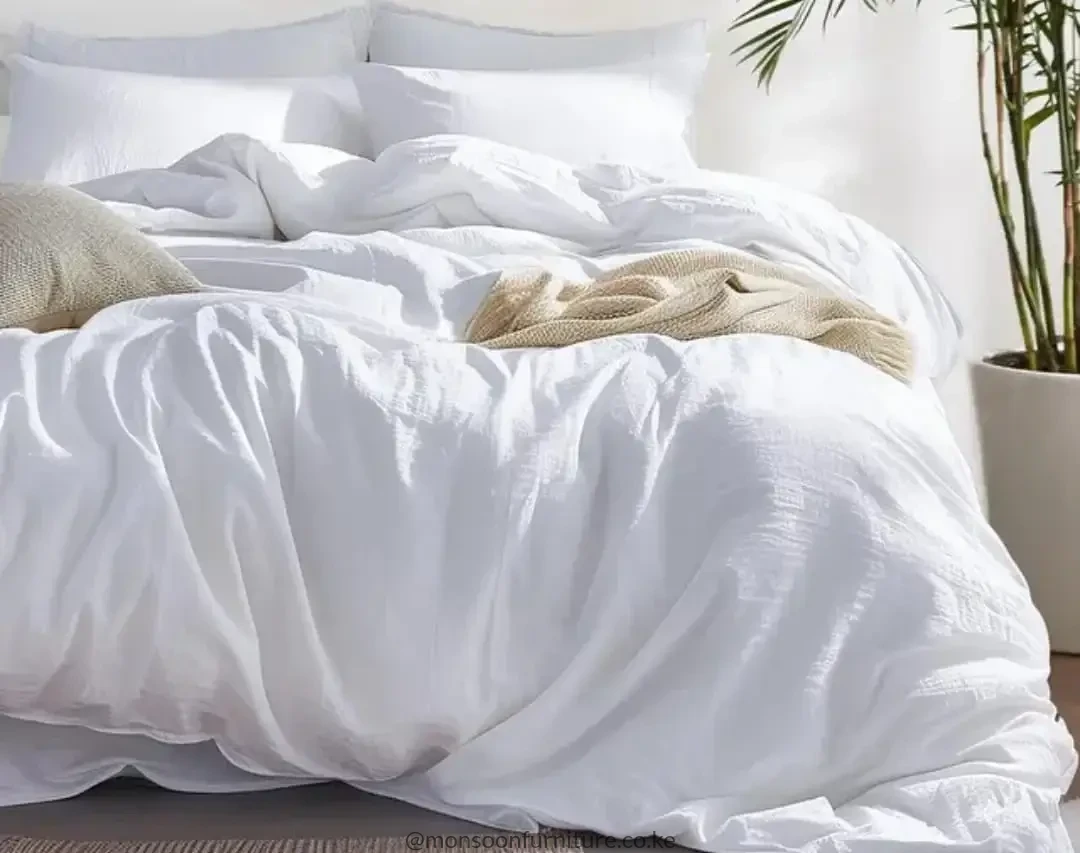 Plain white duvet with a relaxed draped finish arranged on a bed with white pillows.