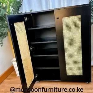 Black shoe cabinet with tan woven rattan door panels, internal shelves, round knobs and small visible wheels.