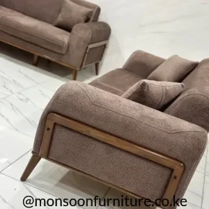 Brown textured sofa with rounded arms, warm-tone rectangular side framing, angled legs and matching seating behind.
