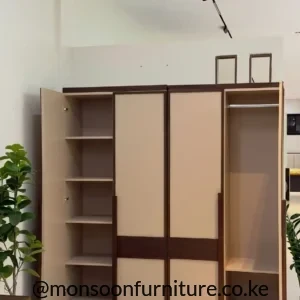 Cream four-door wardrobe with dark wood trim, open shelving and a hanging rail displayed in a furniture showroom.