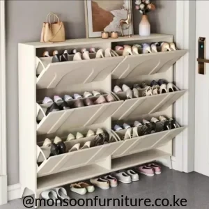 Cream tilt-out shoe cabinet with six angled storage sections, two open lower cubbies and footwear displayed inside.