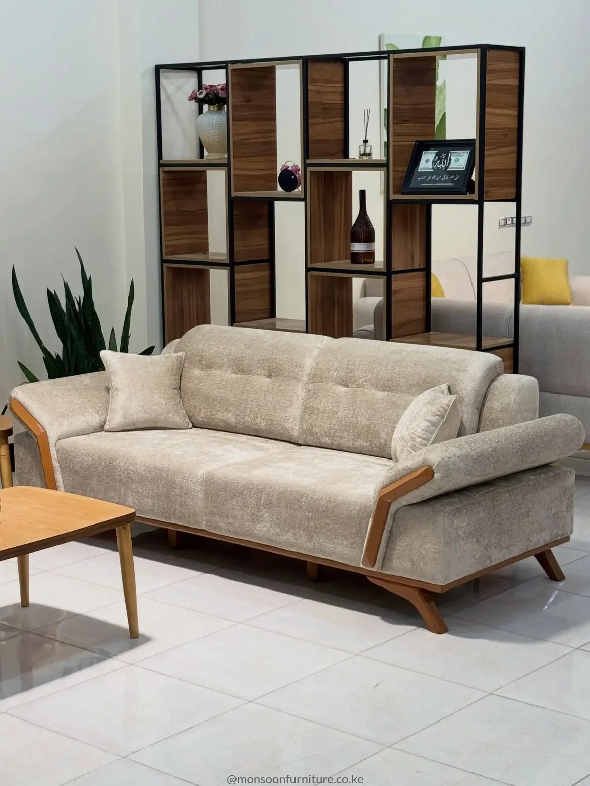 Light cream sofa with padded back sections, rounded arms, warm brown side accents and raised angled legs.