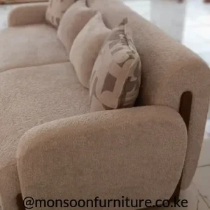 Cream textured sofa with broad rounded arms, curved upholstered back and loose plain and patterned cushions
