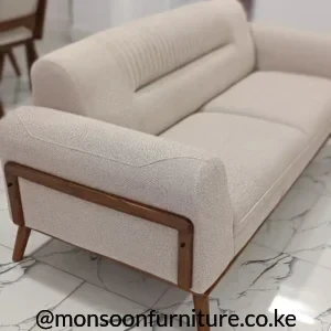 Deep green textured sofa with channel-stitched back, rounded arm, wood-tone trim and tapered legs on marble-look tiles.