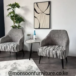 Grey rounded accent chairs with black, white and grey striped seats, integrated arms and slim black legs beside a round table