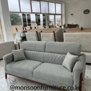 Light grey sofa with chevron-stitched lower back, rounded arms, two seat cushions and slim brown-tone frame accents.