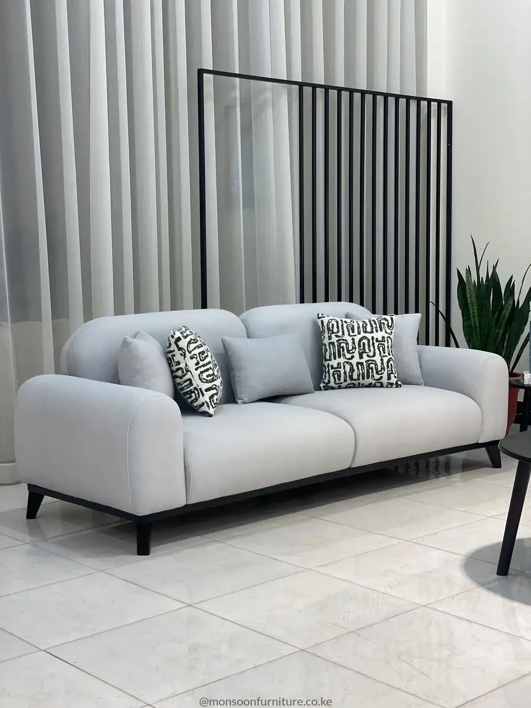 Light grey modern three-seater sofa with rounded arms and black legs for contemporary homes in Kenya
