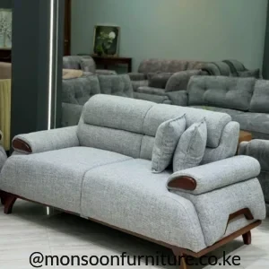Light grey textured sofa with rounded padded arms, warm brown end accents, raised tapered legs and two grey cushions.