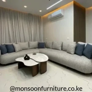 Light grey L-shaped sectional sofa with rounded upholstered arms, grey back cushions and dark blue accent cushions.