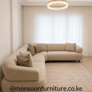 Light beige corner sectional sofa with textured upholstery, rounded padded arms, separate seat cushions and short dark legs.
