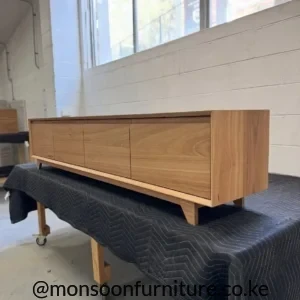ight wood-tone Montserrat entertainment unit with bevelled edges, integrated finger pulls, flush fronts and short block feet.