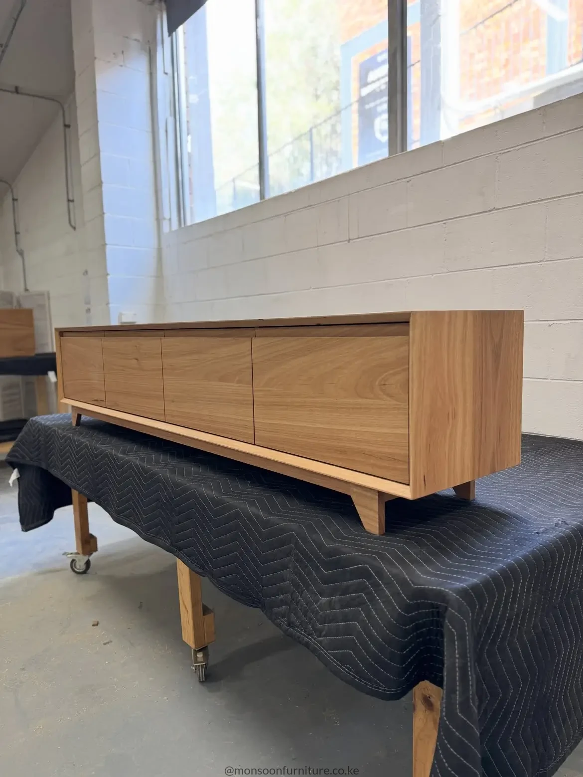 ight wood-tone Montserrat entertainment unit with bevelled edges, integrated finger pulls, flush fronts and short block feet.