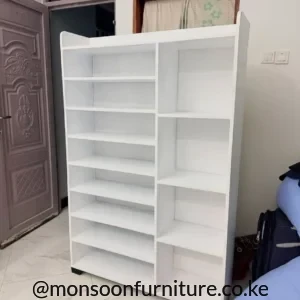 Tall white open shoe storage unit with narrow shelves on the left, larger cubbies on the right and short black feet.