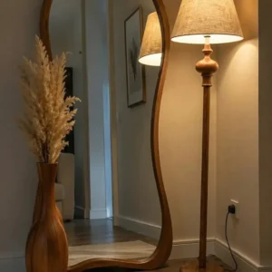 all floor mirror photographed in a neutral interior beside a floor lamp and decorative vase