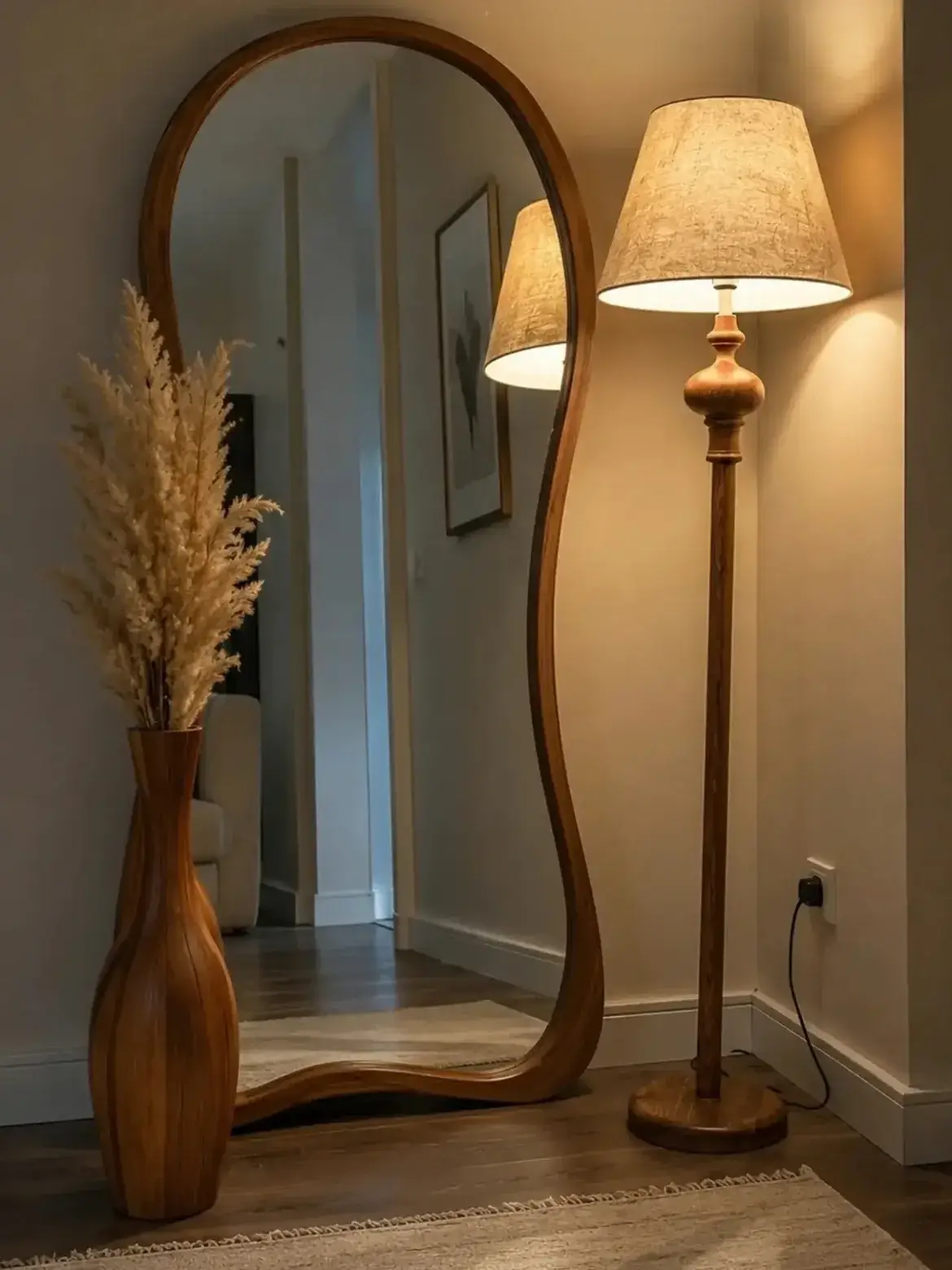 all floor mirror photographed in a neutral interior beside a floor lamp and decorative vase