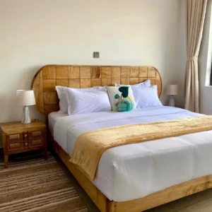 Arched headboard bed frame with warm wood-toned finish and white bedding