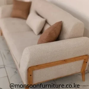 Beige upholstered sofa with textured fabric, rounded arms, brown wooden side rail and raised wooden legs.